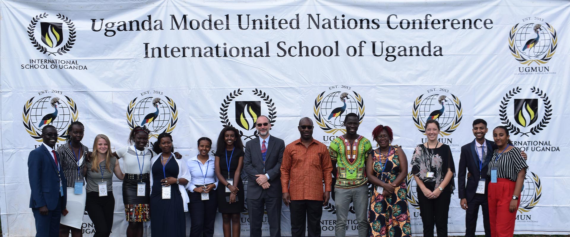 Students and teachers standing in front of a banner that reads 'Uganda Model United Nations Conference International School of Uganda'